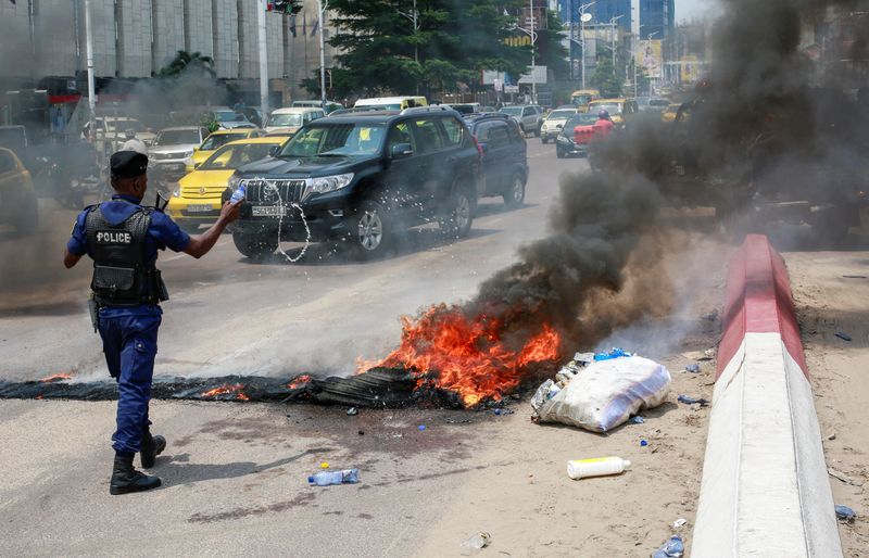 &copy; Reuters. Un policier jette de l'eau sur des pneus en feu après une manifestation près de l'ambassade américaine à Kinshasa, en RDC. /Photo prise le 12 février 2024/REUTERS/Justin Makangara