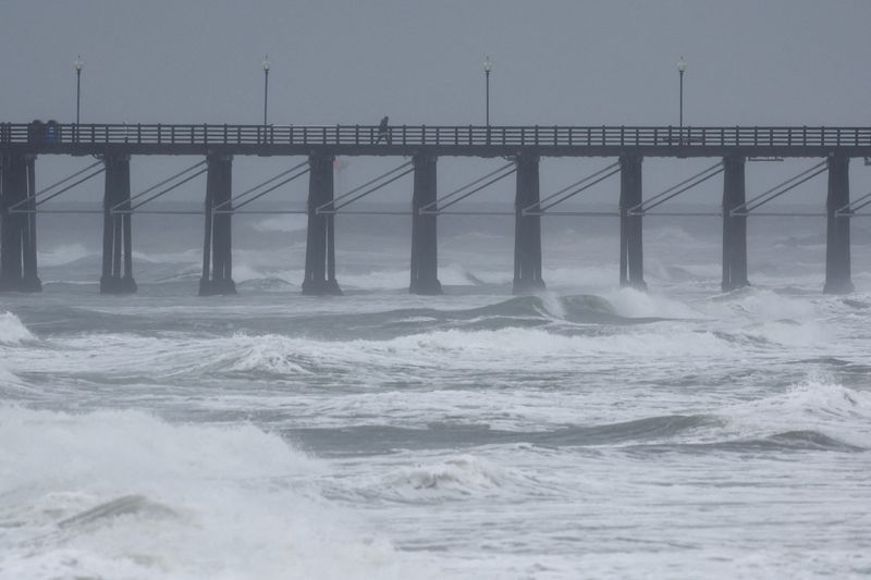 &copy; Reuters. FILE PHOTO: A person walk along a pier as an atmospheric river of rain continues to impact the weather in Oceanside, California, U.S., February 6, 2024.  REUTERS/Mike Blake/File Photo