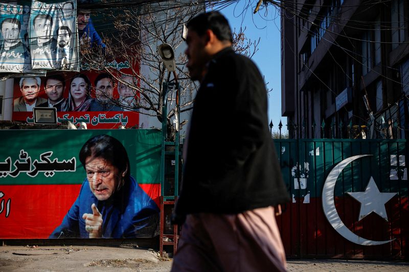 &copy; Reuters. FILE PHOTO: People walk past a banner with a picture of the former Prime Minister Imran Khan outside the party office of Pakistan Tehreek-e-Insaf (PTI), a day after the general election, in Lahore, Pakistan, February 9, 2024. REUTERS/Navesh Chitrakar