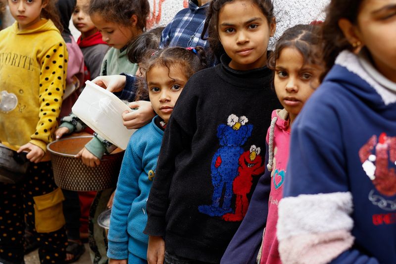 &copy; Reuters. Bambini palestinesi aspettano di ricevere cibo cucinato da una cucina di beneficenza data la scarsità di scorte alimentari, mentre continua il conflitto tra Israele e il gruppo islamista palestinese Hamas, a Rafah, nel sud della Striscia di Gaza, il 13 f
