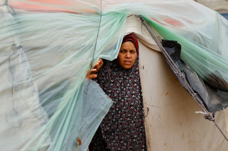 &copy; Reuters. Una donna palestinese sfollata, fuggita dalla sua casa a causa degli attacchi israeliani, si rifugia in una tendopoli durante il conflitto in corso tra Israele e Hamas, a Rafah, a sud della Striscia di Gaza, 13 febbraio 2024. REUTERS/Ibraheem Abu Mustafa
