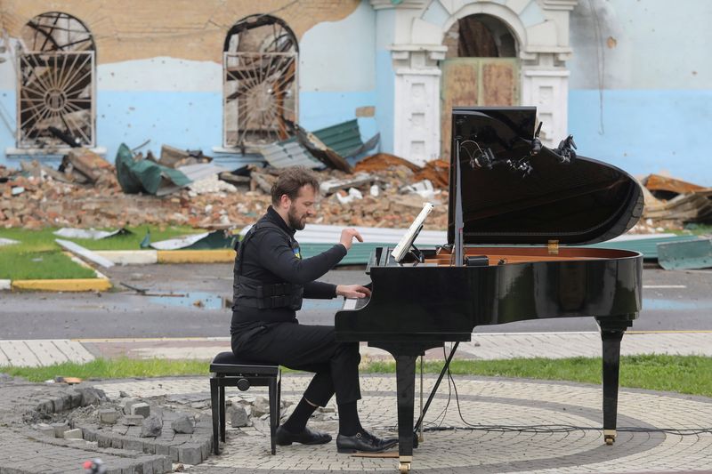 &copy; Reuters. FOTO DE ARCHIVO. El músico lituano Darius Mazintas toca un piano frente a la Casa Central de Cultura destruida durante la invasión rusa, en la ciudad de Irpin, en las afueras de Kiev, Ucrania, el 26 de abril de 2022.  REUTERS/Mykola Tymchenko