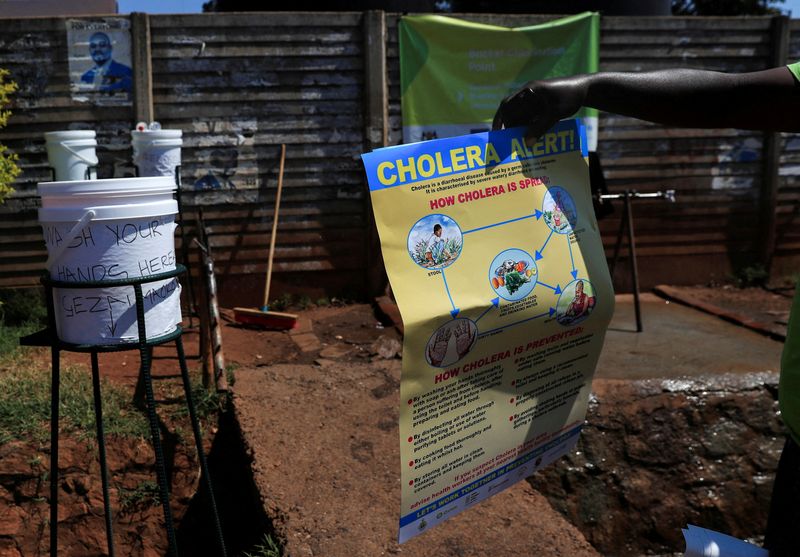&copy; Reuters. FOTO DE ARCHIVO. Un hombre sostiene información en un cartel sobre el cólera afuera de una tienda de campaña en un policlínico en Harare, Zimbabue. November 24, 2023. REUTERS/Philimon Bulawayo