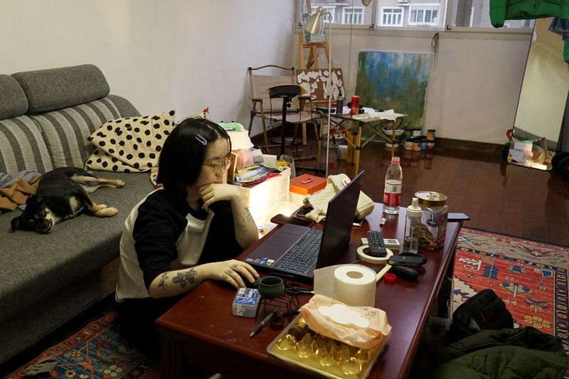 © Reuters. Chu Yi, 23, who is doing a six-month apprenticeship to be a tattoo artist, uses her laptop during an interview with Reuters at her home on the outskirts of Shanghai, China February 5, 2024. REUTERS/Nicoco Chan