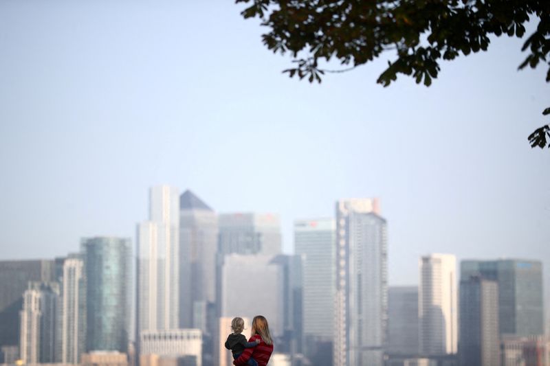 &copy; Reuters. FILE PHOTO: A woman holds a child in front of Canary Wharf skyline, in London, Britain September 14, 2020. REUTERS/Hannah McKay/File Photo