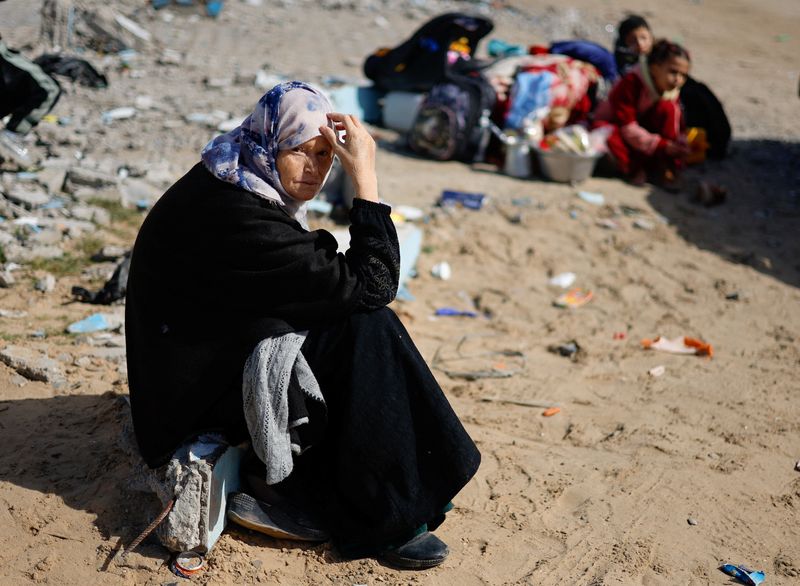 &copy; Reuters. Una mujer sentada junto a unos niños, mientras multitudes de palestinos llegan a Ráfah tras ser evacuados del hospital Nasser en Jan Yunis a causa de la operación terrestre israelí, en el sur de la Franja de Gaza. 15 de febrero de 2024. REUTERS/Mohamm