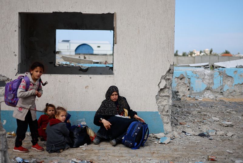 &copy; Reuters. Una donna riposa con i bambini, mentre i palestinesi arrivano a Rafah dopo essere stati evacuati dall'ospedale Nasser di Khan Younis a causa dell'offensiva di terra israeliana, nell'ambito del conflitto in corso tra Israele e Hamas, nel sud della Striscia