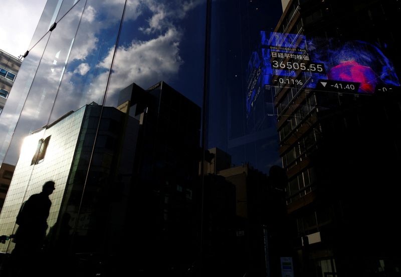 &copy; Reuters. A pedestrian is reflected on a glass of a business building while an electric board showing Nikkei index is seen in the building  at a business district in Tokyo, Japan January 23, 2024. REUTERS/Kim Kyung-Hoon/File Photo