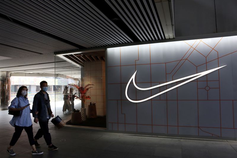 &copy; Reuters. Diverse persone davanti al logo Nike a Pechino, in Cina. REUTERS/Florence Lo/