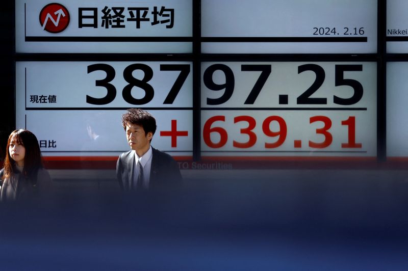 © Reuters. شخصان يسيران أمام شاشة تعرض بيانات مؤشر نيكي الياباني خارج شركة للوساطة المالية في طوكيو يوم الجمعة. تصوير: إيسي كاتو - رويترز.
