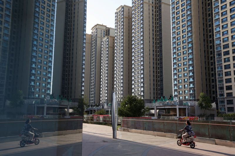 © Reuters. A woman rides a scooter past residential buildings at an Evergrande residential complex in Beijing, China September 27, 2023. REUTERS/Florence Lo/File Photo