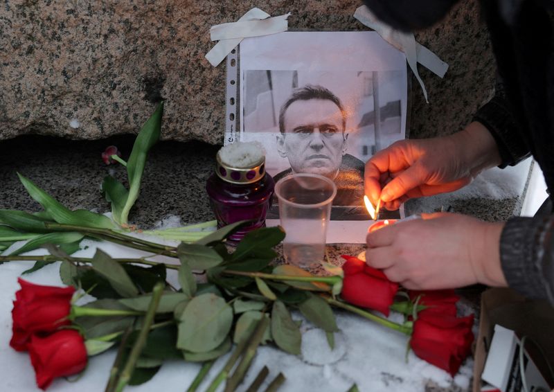 © Reuters. A person lights a candle next to a portrait of Russian opposition leader Alexei Navalny at the monument to the victims of political repression following Navalny's death, in Saint Petersburg, Russia, February 16, 2024. REUTERS/Stringer