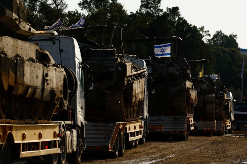 &copy; Reuters. Israeli flags are seen as tanks and armoured personnel carriers wait to be unloaded outside Kibbutz Be'eri, amid the ongoing conflict between Israel and the Palestinian Islamist group Hamas, on the Israeli side of the border between Israel and the Gaza, F