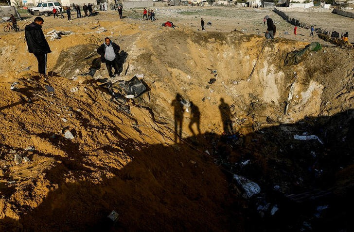 &copy; Reuters. Palestinesi si riuniscono vicino a un cratere sul luogo di un attacco israeliano a una casa, nel corso del conflitto in corso tra Israele e il gruppo islamista palestinese Hamas, a Rafah, nel sud della Striscia di Gaza, il 18 febbraio 2024. REUTERS/Mohamm