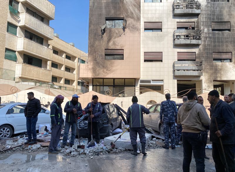 © Reuters. أشخاص وعمال يقفون أمام مبنى تضرر جراء ما قالت وسائل إعلام سورية رسمية إنه هجوم صاروخي إسرائيلي في كفرسوسة بدمشق يوم الأربعاء. تصوير: فراس مقدسي - رويترز.