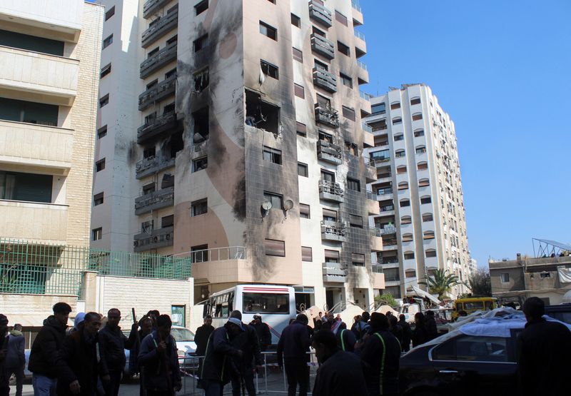 © Reuters. Varias personas se reúnen cerca de un edificio dañado después de que, según informan los medios de comunicación estatales sirios, varios misiles israelíes alcanzaron un edificio residencial en el distrito de Kafr Sousa, Damasco, Siria. 21 de febrero de 2024. REUTERS/Firas Makdesi