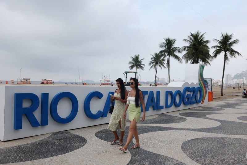 &copy; Reuters. Mulheres passam por cartaz do G20 na praia de Copacabana
21/02/2024
REUTERS/Pilar Olivares