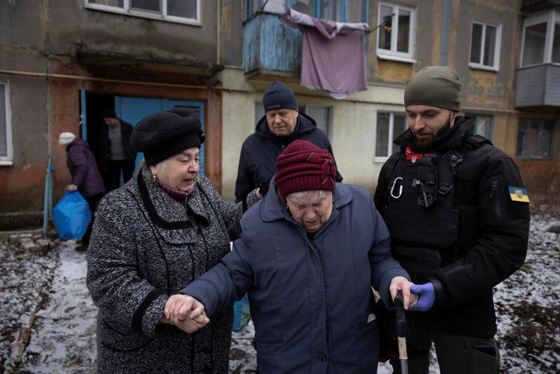 &copy; Reuters. 　２月２１日、ウクライナ東部ドネツク州の要衝アブデーフカを先週掌握したロシア軍は近隣の町への攻撃を続けている。写真はアブデーフカの自宅から避難する女性を助けるボランティア