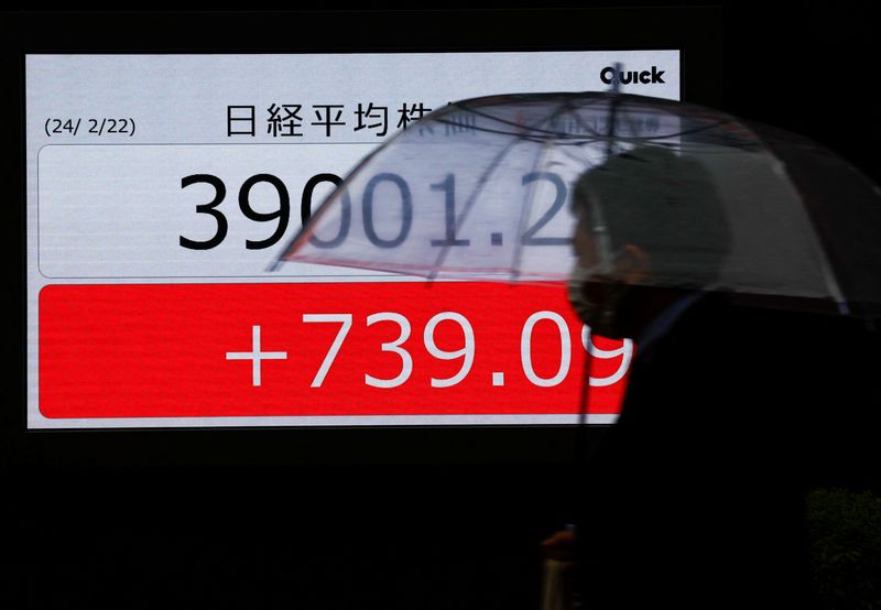 © Reuters. A passerby walks past electronic screens displaying Japan's Nikkei share average, which surged past an all-time record high scaled in December 1989, outside a brokerage in Tokyo, Japan February 22, 2024. REUTERS/Issei Kato