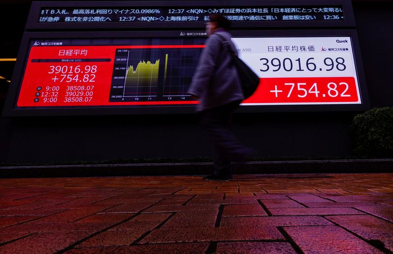 © Reuters. A passerby walks past in front of electronic screens displaying Japan's Nikkei share average, which surged past an all-time record high scaled in December 1989, outside a brokerage in Tokyo, Japan February 22, 2024. REUTERS/Issei Kato