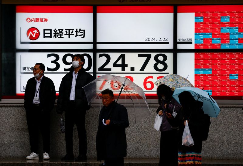 © Reuters. Passersby stand in front of electronic screens displaying Japan's Nikkei share average, which surged past an all-time record high scaled in December 1989, outside a brokerage in Tokyo, Japan February 22, 2024. REUTERS/Issei Kato