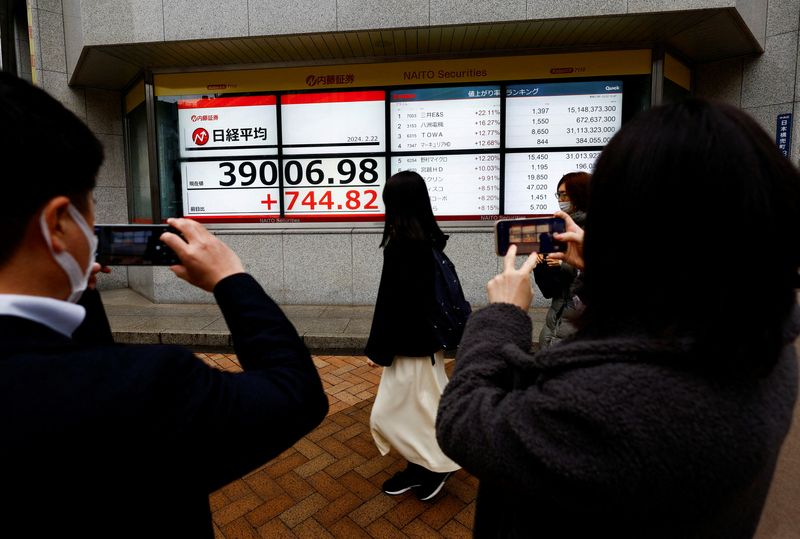 &copy; Reuters. People using their smartphones take photos of electronic screens displaying Japan's Nikkei share average, which surged past an all-time record high scaled in December 1989, outside a brokerage in Tokyo, Japan February 22, 2024. REUTERS/Issei Kato