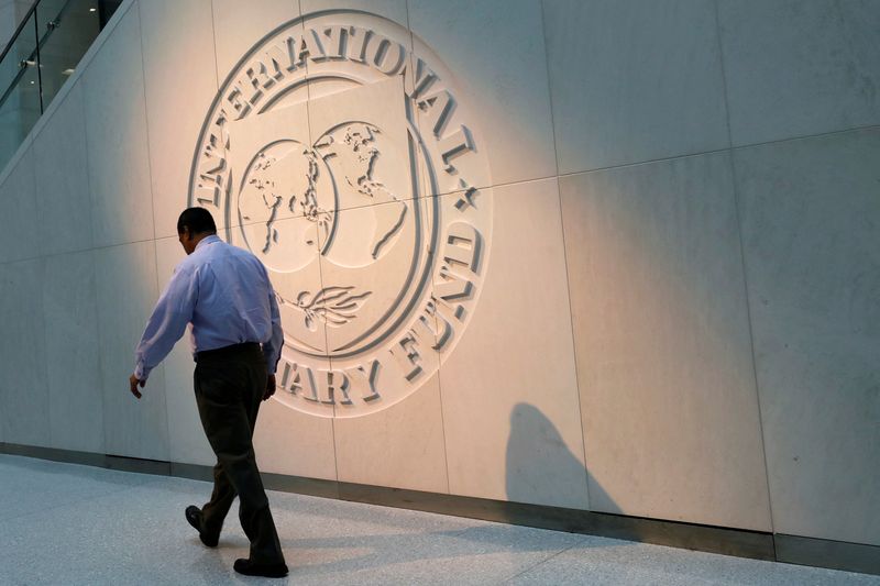 &copy; Reuters. رجل يمر أمام شعار صندوق النقد الدولي على مقره في واشنطن في صورة من أرشيف رويترز.