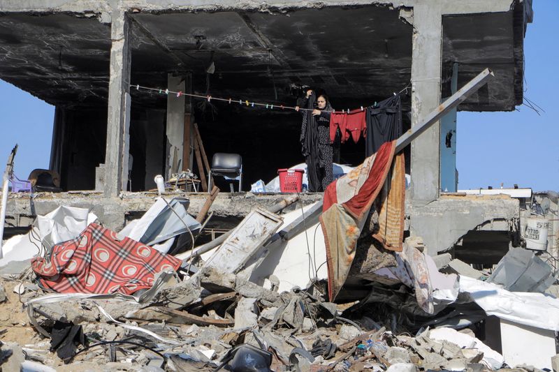 &copy; Reuters. Una donna palestinese stende i panni accanto a un edificio distrutto, durante il conflitto in corso tra Israele e Hamas, nel campo profughi di Jabalia, nel nord della Striscia di Gaza, 22 febbraio 2024. REUTERS/Mahmoud Issa