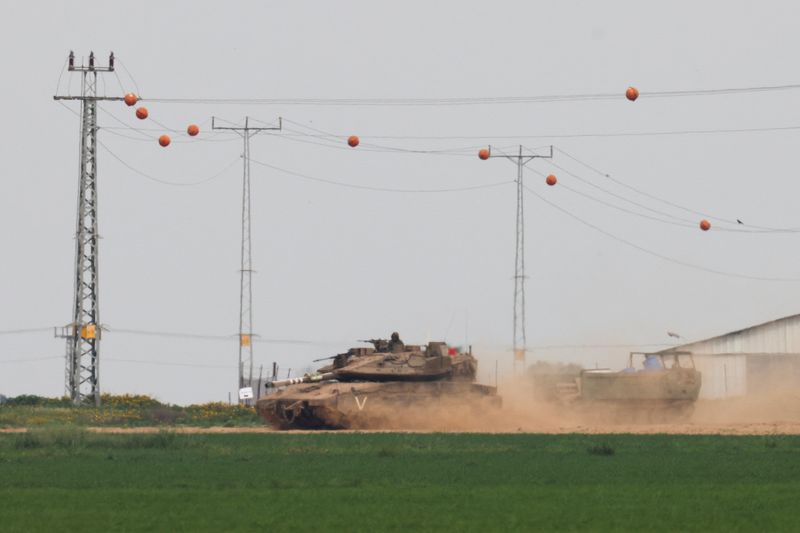&copy; Reuters. دبابة إسرائيلية تسحب ناقلة جنود قرب الحدود مع قطاع غزة كما شوهدت من إسرائيل يوم الجمعة. تصوير : سوزانا فيرا - رويترز .    