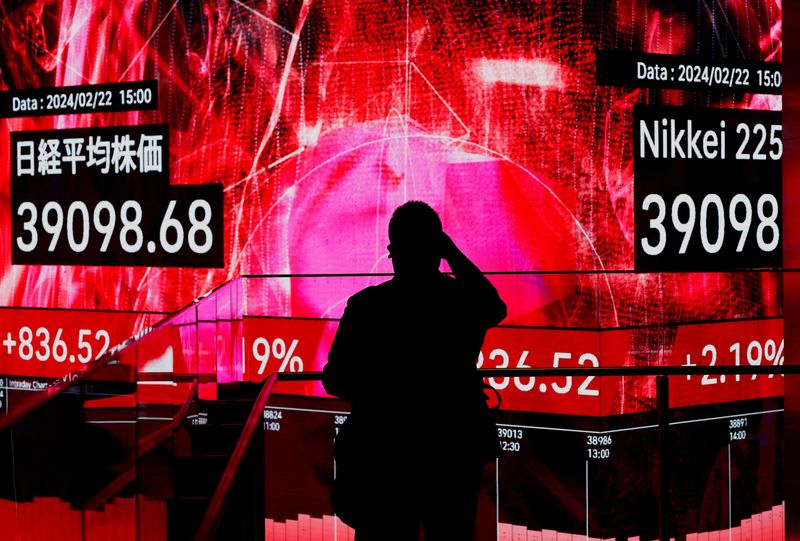 &copy; Reuters. FILE PHOTO: A visitor using his smartphone takes photos of an electronic screen displaying Japan's Nikkei share average, which surged past an all-time record high scaled in December 1989, inside a building in Tokyo, Japan February 22, 2024.  REUTERS/Issei