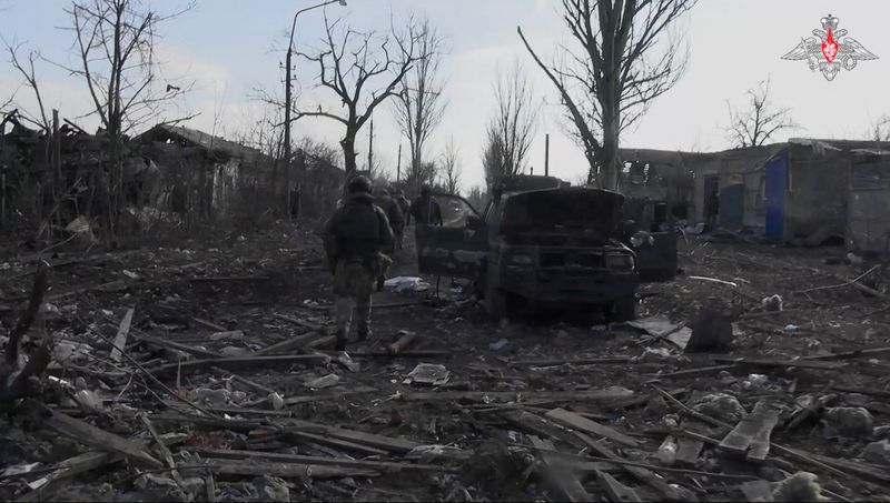 &copy; Reuters. Photo des militaires russes qui marchent au milieu des décombres, à proximité d'une voiture endommagée, à Avdiivka. /Photo prise le 22 février 2024 à Avdiivka, Ukraine/REUTERS/Ministère russe de la Défense
