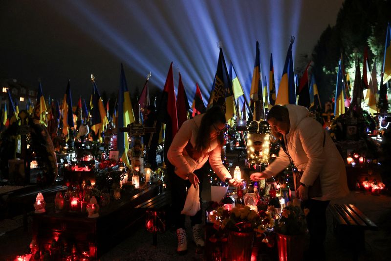 © Reuters. Personas visitan la tumba de su pariente, un miembro del servicio ucraniano muerto en combate contra las tropas rusas, antes del segundo aniversario del ataque de Rusia a Ucrania, en un cementerio militar en Lviv, Ucrania, el 23 de febrero de 2024.REUTERS/Roman Baluk