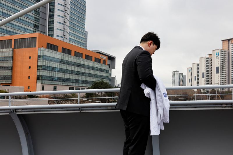 &copy; Reuters. Ryu O. Hada, 25, holds his white coat in front of the hospital where he worked in Seoul. REUTERS/Kim Soo-Hyeon