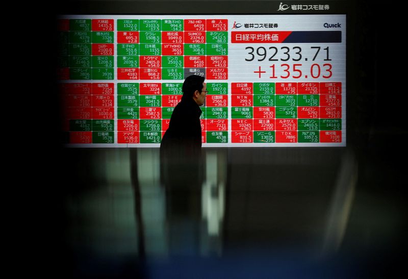 &copy; Reuters. A man passes by an electronic screen displaying Japan's Nikkei share average as it scaled an all-time closing high in Tokyo, Japan February 26, 2024. REUTERS/Issei Kato