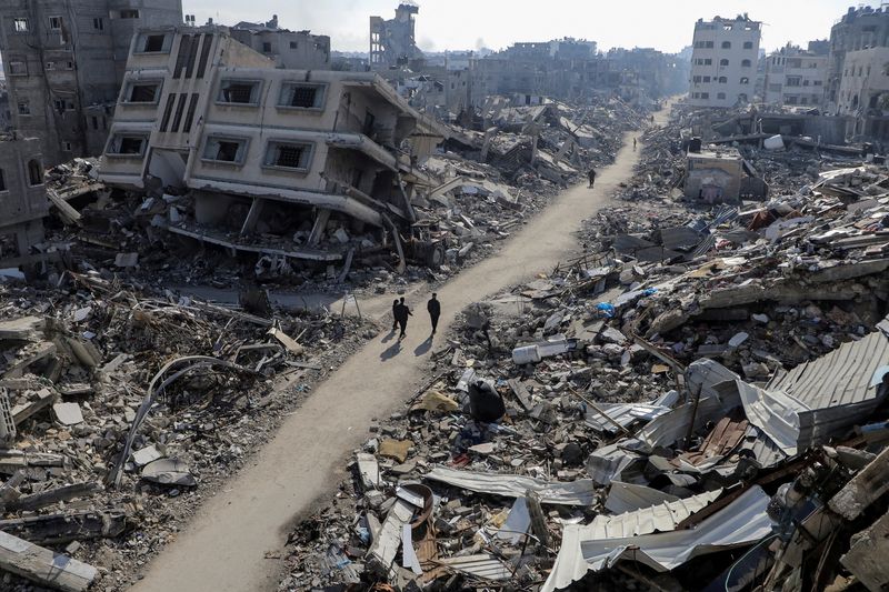 &copy; Reuters. فلسطينيون يسيرون بجوار منازل مدمرة،وسط الصراع المستمر بين إسرائيل وحركة حماس الإسلامية الفلسطينية، في شمال قطاع غزة يوم 22 فبراير شباط 2024. ت