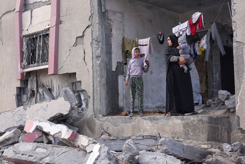 © Reuters. Una mujer palestina sostiene a su hijo en una casa dañada por los ataques israelíes, mientras continúa el conflicto entre Israel y Hamás, en Rafah, en el sur de la Franja de Gaza. 27 de febrero de 2024. REUTERS/Saleh Salem  
