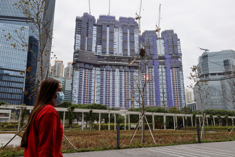 © Reuters. A woman walks in front of an under-construction residential building, in Hong Kong, China, February 27, 2024. REUTERS/Tyrone Siu