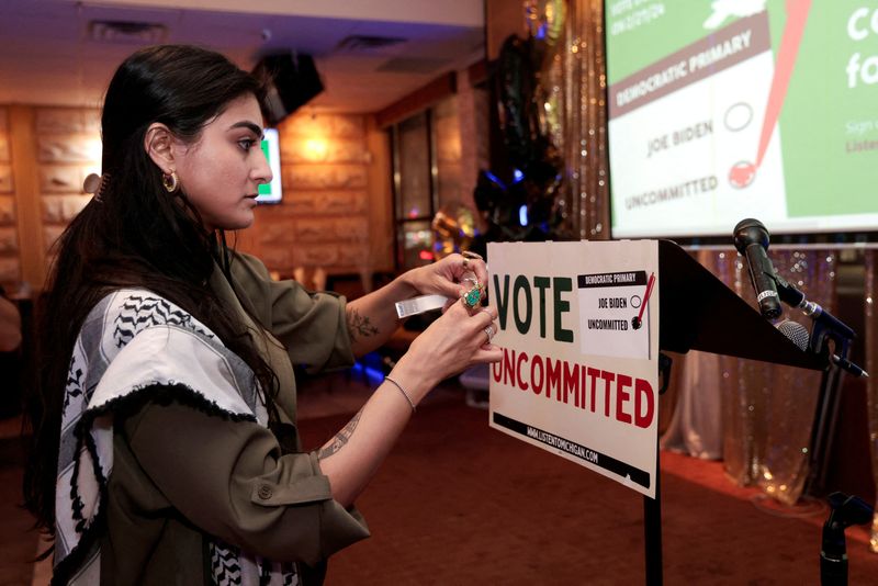 &copy; Reuters. La activista Natalia Latif pega un cartel de "Vote Uncommitted" en la tribuna de oradores durante una reunión de la noche electoral en la que demócratas y republicanos celebran sus elecciones primarias presidenciales en Dearborn, Michigan, Estados Unido