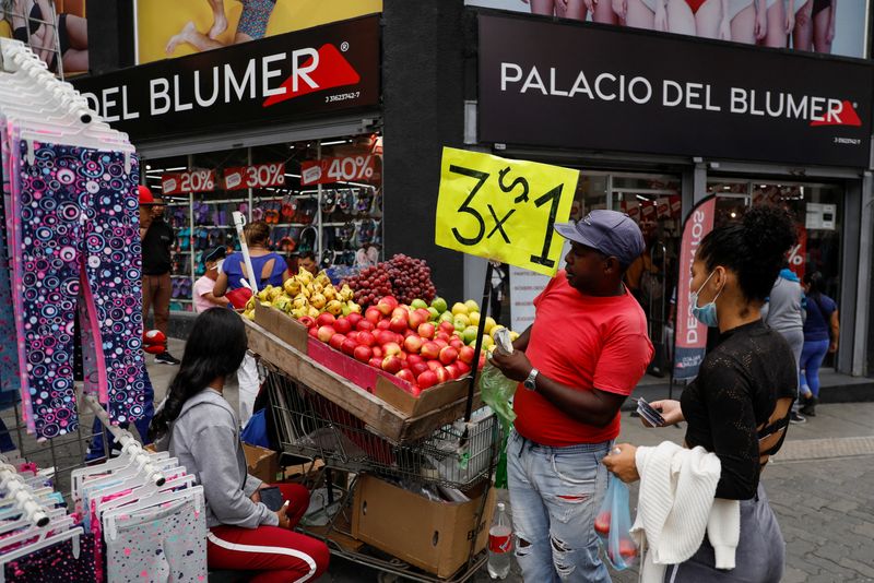 &copy; Reuters. FILE PHOTO: A woman buys apples at a street stand with a sign reading "3 for 1 U.S. Dollar," in Caracas, Venezuela August 25, 2022. REUTERS/Leonardo Fernandez Viloria/File Photo