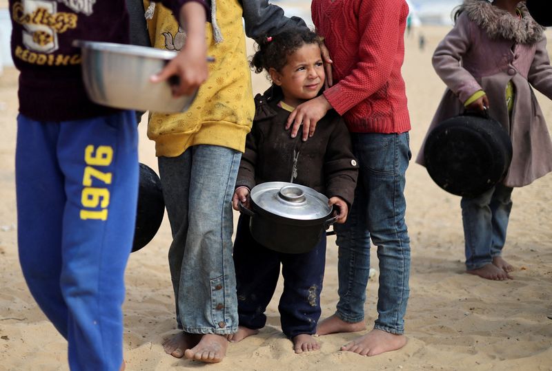 © Reuters. FILE PHOTO: Displaced Palestinian children wait to receive free food at a tent camp, amid food shortages, as the conflict between Israel and Hamas continues, in Rafah in the southern Gaza Strip, February 27, 2024. REUTERS/Ibraheem Abu Mustafa/File Photo