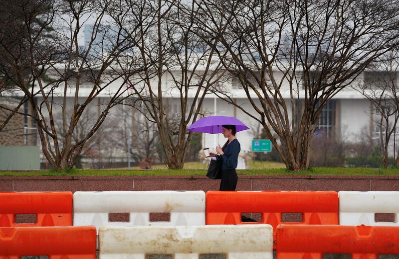 © Reuters. A woman walks along a road under construction near the Kennedy Center, on a rainy morning in Washington, U.S., February 28, 2024. REUTERS/Kevin Lamarque