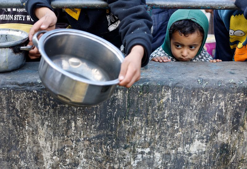 &copy; Reuters. طفل فلسطيني ينظر بينما ينتظر الحصول على طعام تطهوه مؤسسة خيرية في ظل نقص المواد الغذائية في رفح بجنوب قطاع غزة يوم 20 فبراير شباط 2023. تصوير: مح