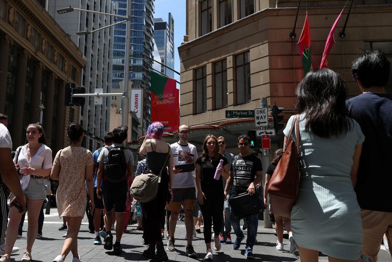 &copy; Reuters. FILE PHOTO: People cross a busy street under holiday decorations in the city centre of Sydney, Australia, December 17, 2020.  REUTERS/Loren Elliott/File Photo