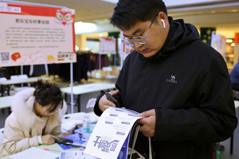 &copy; Reuters. Zhang Baichuan, 23, checks a job advertisement at a job fair in Shijiazhuang, Hebei province, China February 24, 2024. REUTERS/Florence Lo