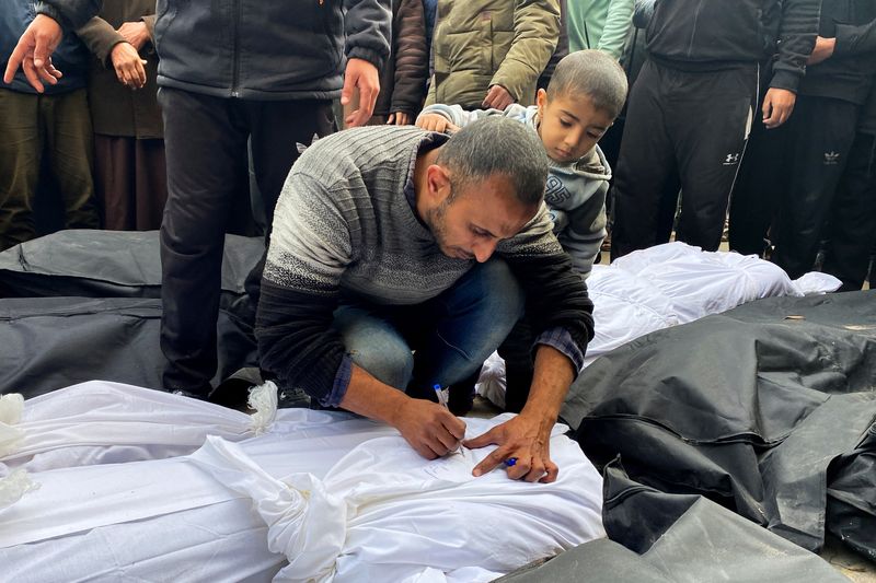 &copy; Reuters. فلسطيني يكتب اسما على كفن يغطي جثمان شخص قتل في غارات إسرائيلية في مستشفى الأقصى بدير البلح بوسط قطاع غزة يوم 23 فبراير شباط 2024. تصوير: دعاء رو