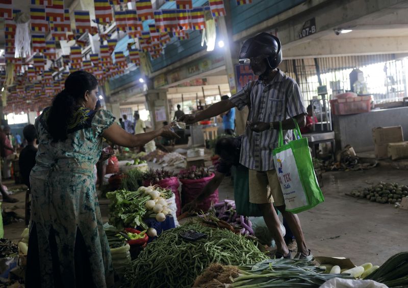 &copy; Reuters. FILE PHOTO: A customer pays for the vegetables he bought, as Sri Lanka's key inflation rate eases to 25.2% in May, at a stall at a main market in Colombo, Sri Lanka June 1, 2023. REUTERS/Dinuka Liyanawatte/File photo