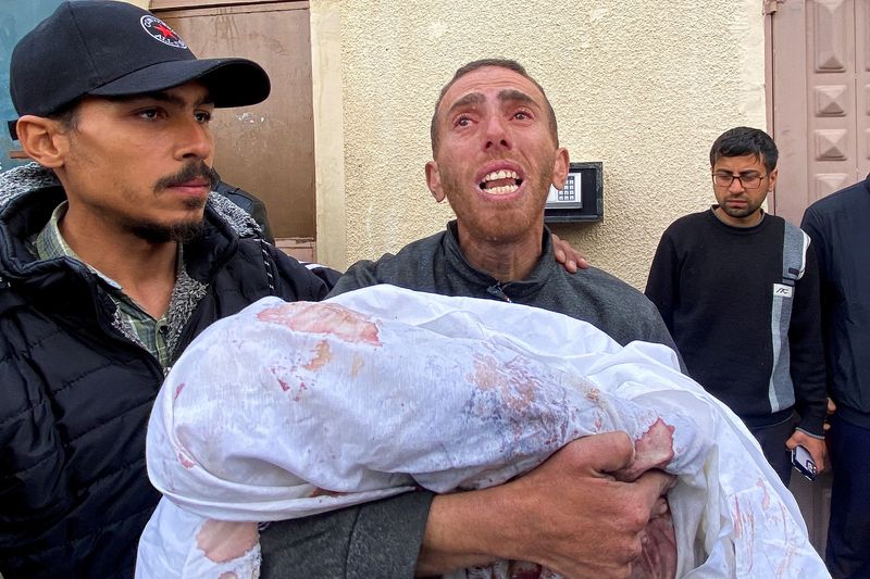 &copy; Reuters.  رجل يدعى أحمد عزام يحمل جثمان ابنه مهند الذي ولد خلال الحرب وقتل جراء غارة إسرائيلية في مستشفى الأقصى في دير البلح وسط قطاع غزة يوم 23 فبراير 