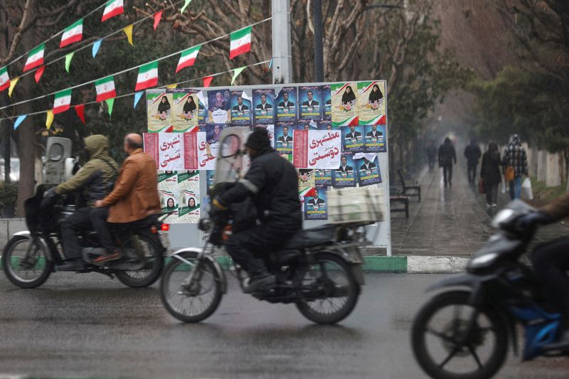 &copy; Reuters. إيرانيون يركبون دراجات نارية يمرون بجوار ملصقات دعائية قبل الانتخابات البرلمانية في طهران يوم الأربعاء. صورة لرويترز من وكالة غرب آسيا للأ