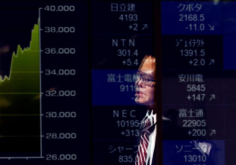&copy; Reuters. FILE PHOTO: A passerby is reflected on an electronic screen displaying a graph showing recent Japan's Nikkei share average movements and stock prices as the share average hits a record high in Tokyo, Japan February 26, 2024. REUTERS/Issei Kato/File Photo