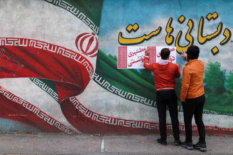 &copy; Reuters. رجلان يعلقان ملصقات لحملة انتخابية على الحائط خلال اليوم الأخير من الحملة الانتخابية في طهران يوم 28 فبراير شباط 2024. صورة لرويترز من وكالة أن